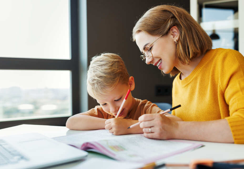 cheerful mother doing homework with son at home