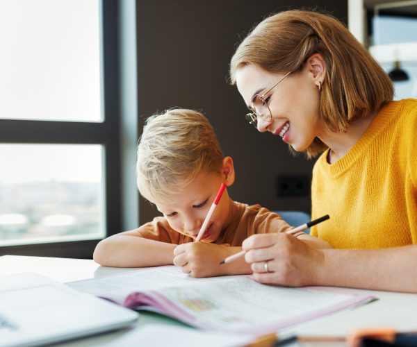 cheerful mother doing homework with son at home
